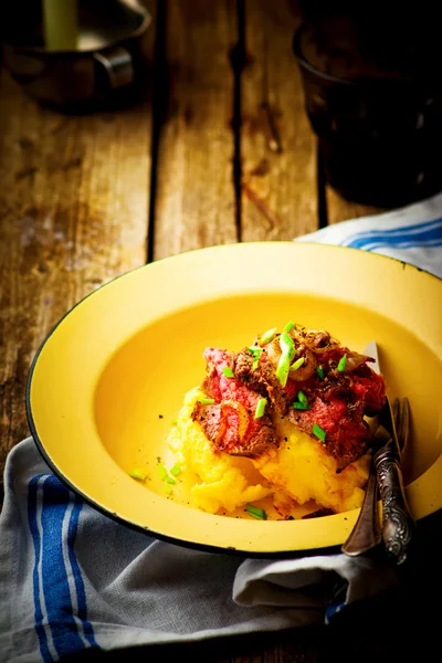 Roast beef and polenta in an iron bowl on a wooden table. — Stock Photo, Image