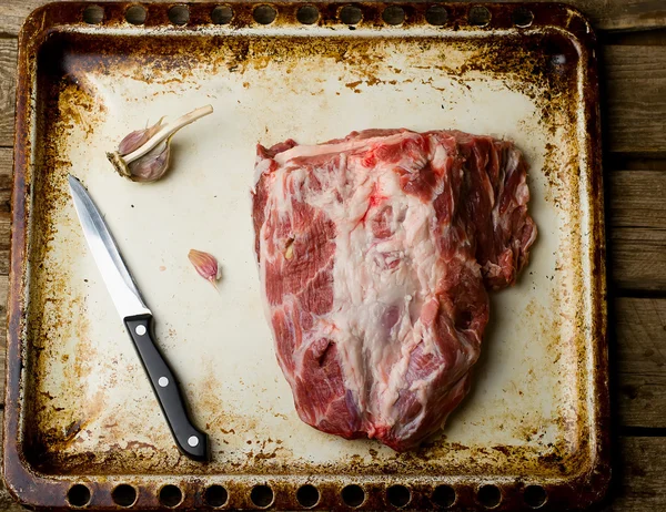 Piece of crude pork ready for roasting on a baking sheet. — Stock Photo, Image