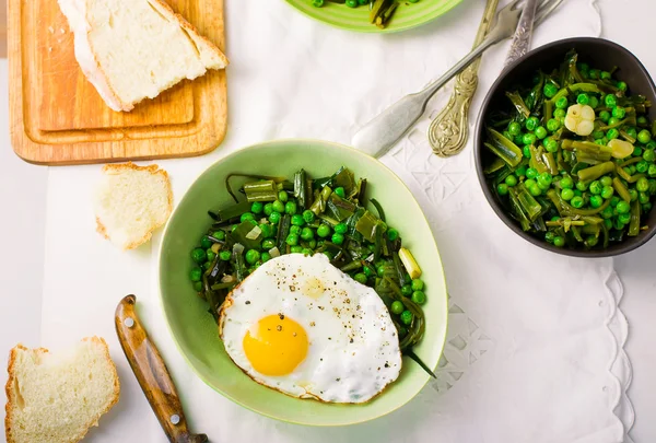 Stewed green peas with fried eggs — Stock Photo, Image