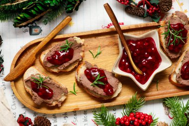 Noel arkaplanında tavuk ciğeri ezmesi ve yaban mersini soslu crostini.