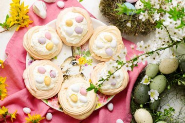 Çırpılmış krema ve dekoratif çikolata yumurtalı paskalya kreması yuvaları.