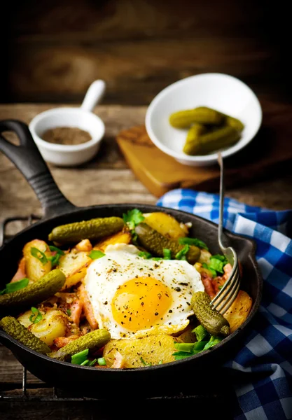 Domácí snídaně z brambor se slaninou a smaženými vejci v litinové pánvi. — Stock fotografie