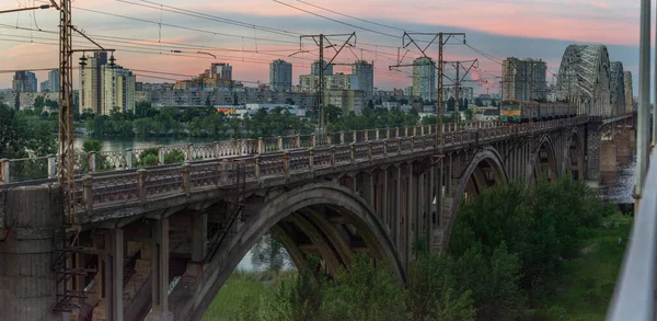火车在日落后如期在乌克兰基辅的老铁路桥上行驶 — 图库照片