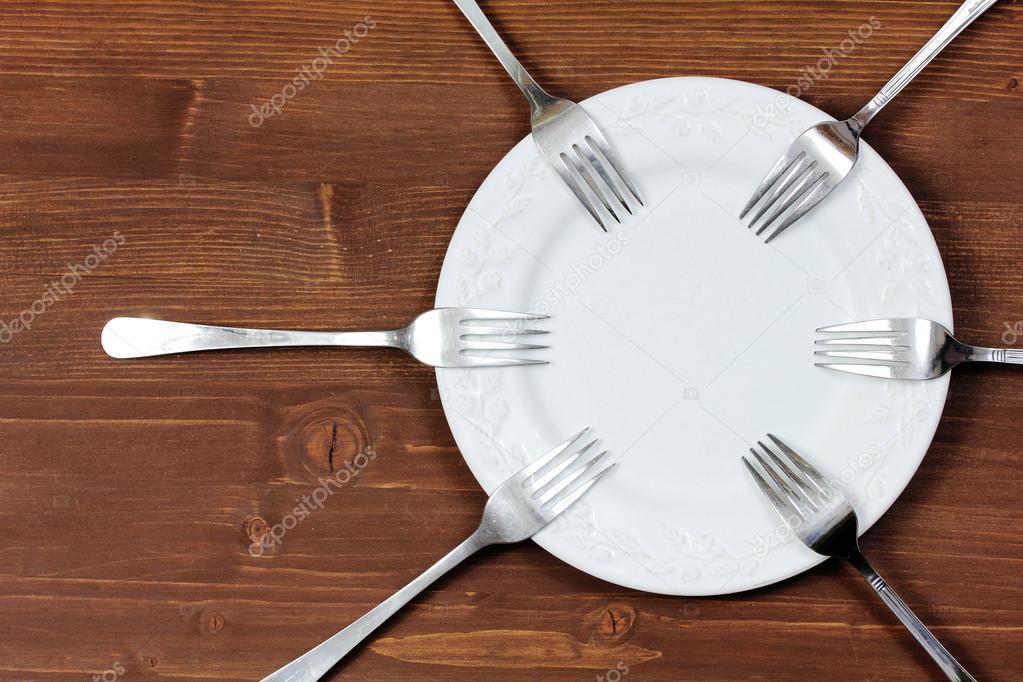 Plate with forks on wooden background
