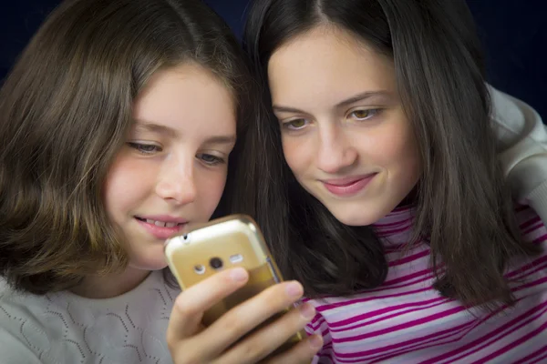 Porträt zweier süßer Schwestern, die aufs Handy schauen — Stockfoto