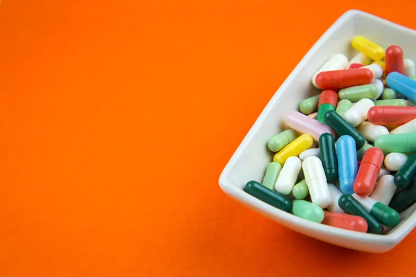 Wiele tabletek na pomarańczowym tle — Zdjęcie stockowe