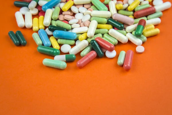 Muitas pílulas no fundo laranja — Fotografia de Stock