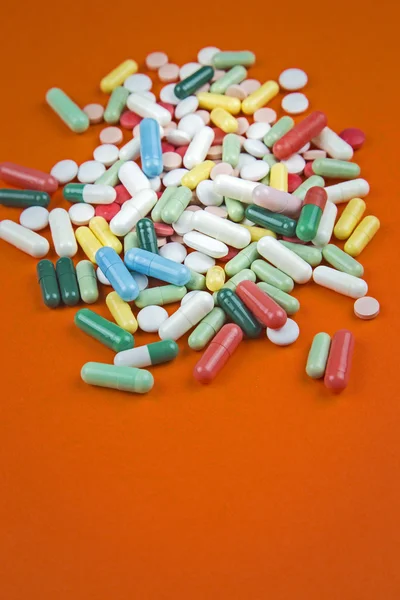 Lots of pills on orange background — Stock Photo, Image