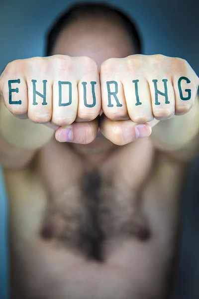 A palavra ENDURING escrito nos punhos de um homem — Fotografia de Stock