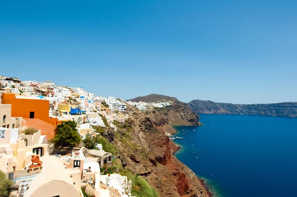 Oia Stadt mit in den Felsen gehauenen weiß getünchten Gebäuden am Rande der Caldera-Klippen auf der Insel Thira (Santorini), Griechenland. — Stockfoto