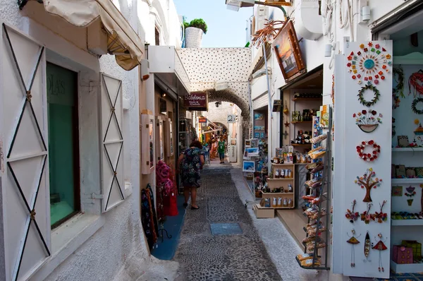 SANTORINI, FIRA-28 DE JULIO: Calle comercial con tiendas de souvenirs el 28 de julio de 2014 en la ciudad de Fira en la isla de Santorini, Grecia. Firá es la capital moderna de la isla griega del Egeo, Santorini . — Foto de Stock