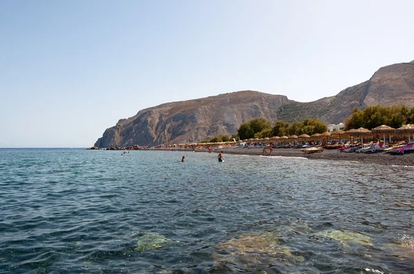 Turisták a Kamari strandtól napozhat. Santorini-sziget, Görögország. — Stock Fotó