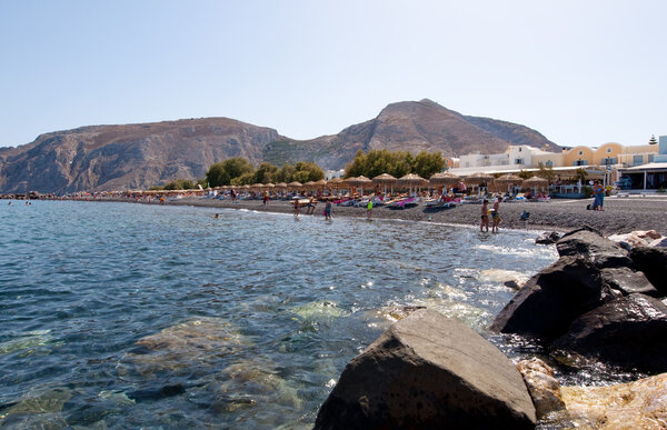 SANTORINI,FIRA-JULY 28: Tourists sunbathe on the Kamari Beach on July 28,2014 on the island of Santorini(Thira), Greece. Kamari beach is located on the eastern coast of Santorini.