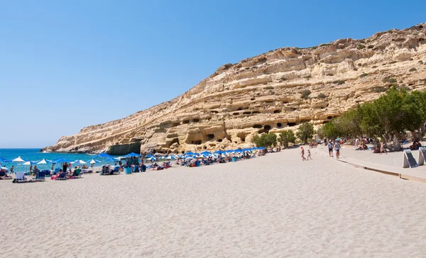 CRETE,GREECE-JULY 22: Holidaymakers on Matala beach with the caves on July 22,2014 Crete island, Greece. — 图库照片