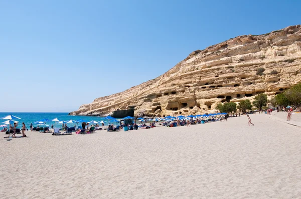 CRETE,GREECE-JULY 22: Tourists on Matala beach with the caves on Libyan sea on July 22,2014 Crete island, Greece. — Stockfoto