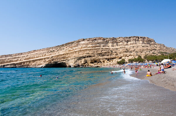 CRETE,GREECE-JULY 22: Tourists on Matala beach with the caves on Libyan sea on July 22,2014 Crete, Greece.