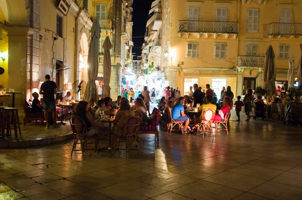 CORFU-AUGUST 25: Tourists have dinner in a local restaurant at night on August 25, 2014 in Kerkyra town on the Corfu island, Greece. — Stock Photo, Image