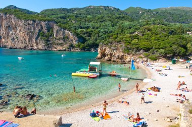 Corfu-Ağustos 26: Bir Palaiokastritsa Beach, insanlar sahilde Ağustos'ta güneşlenmek 26,2014, Corfu Island, Yunanistan. Palaiokastritsa kuzey batısında Korfu ünlü plajları ile bir köydür.
