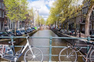 Amsterdam Kanal Köprüsü ve banka boyunca park etmiş arabaların Motosiklet ile. Hollanda.