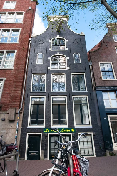 Amsterdam, Nizozemsko-duben 27: Architektura Tipical Amsterdam a s celkovou kapacitou kolo v popředí na 27 dubna 2015 v Amsterdamu, Nizozemsko. — Stock fotografie