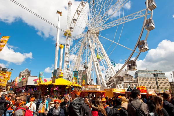 AMSTERDÃO, PAÍSES BAIXOS-ABRIL 27: Dia do Rei na Praça da Barragem com parque de diversões em abril 27.2015 em Amsterdã . — Fotografia de Stock