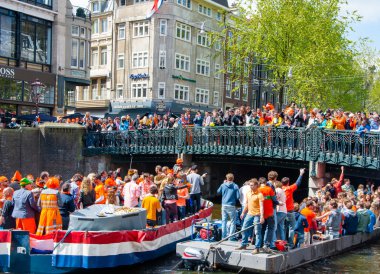 AMSTERDAM, NETHERLANDS-APRIL 27: Party Boat with crowd of people on the bridge on King's Day on April 27,2015.