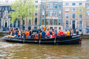 AMSTERDAM-APRIL 27: Crowd of people have dance party on a boat King's Day along the Singel canal on April 27,2015, the Netherlands.