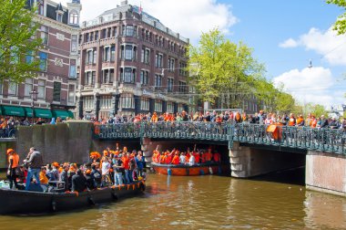 AMSTERDAM-APRIL 27:  King's Day (Koningsdag) boating on the Singel canal,  crowd of people watch the festival on the bridge on April 27, 2015.