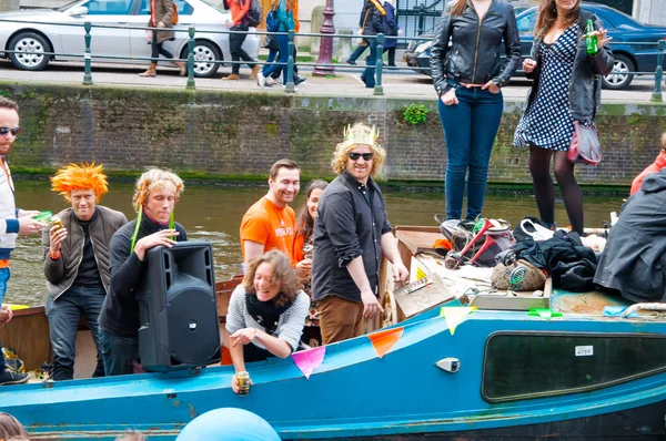 AMSTERDAM,NETHERLANDS-APRIL 27: Cheerful locals and tourists in orange have fun on a boat during King's Day on April 27,2015. — Stock Photo, Image