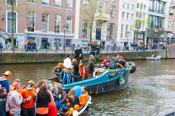 AMSTERDAM,NETHERLANDS-APRIL 27: Cheerful people in orange have fun on a boat during King's Day on April 27,2015. — Stockfoto