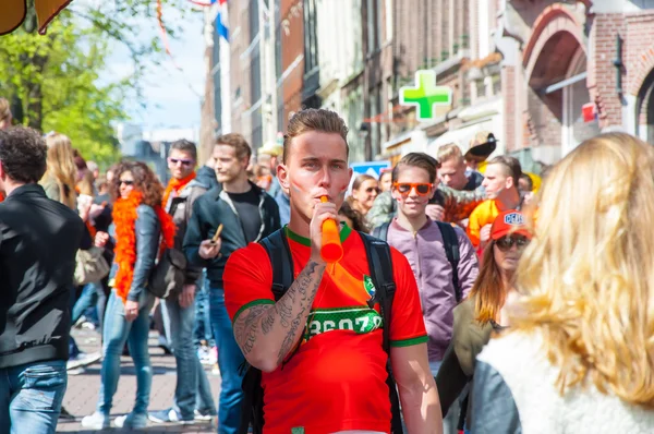 AMSTERDAM-APRIL 27: Undefined person play the pipe, crowd of People have fun on Amsterdam street During King's Day on April 27,2015. — Stockfoto