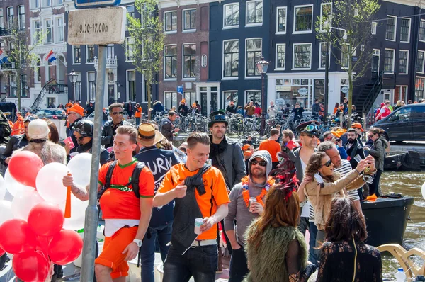 AMSTERDAM-APRIL 27: Locals and tourists in orange have fun on a boat during King's Day, the Singel canal on April 27,2015, the Netherlands. — Stockfoto