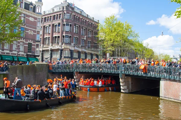 AMSTERDAM-ABRIL 27: Día del Rey (Koningsdag) navegando en el canal de Singel, multitud de personas ven el festival en el puente el 27 de abril de 2015 . — Foto de Stock