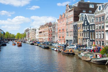 AMSTERDAM-APRIL 27: Amsterdam cityscape with boats along the bank of the canal on King's Day, on April 27,2015.