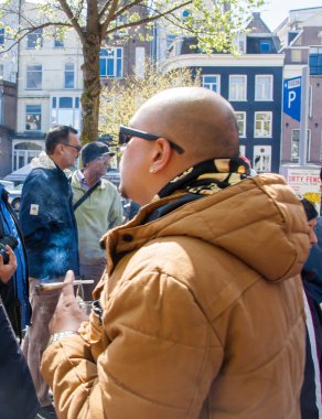AMSTERDAM-APRIL 27: Unidentified man smokes marijuana on Amsterdam street during King's Day on April 27,2015.