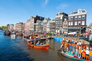 AMSTERDAM-APRIL 27: People in orange on boats participate in celebrating King's Day through Singel canal on April 27,2015 the Netherlands.