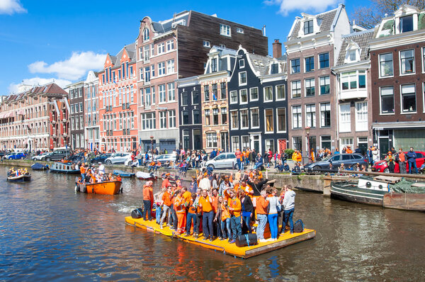 AMSTERDAM-APRIL 27: Happy People celebrate King's Day along the Singel canal on the orange raft, crowd enjoy the festival from the bank of the canal on April 27,2015, the Netherlands.