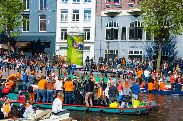 AMSTERDAM-APRIL 27: Party Boat on Singel canal with crowd of people on the street during King's Day on April 27,2015. — Stockfoto