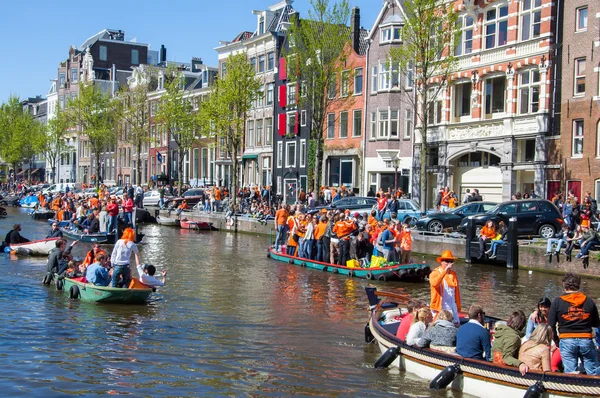 AMSTERDAM-ABRIL 27: Barco de fiesta con multitud de personas a lo largo del canal en el Día del Rey el 27 de abril de 2015, Holanda . — Foto de Stock