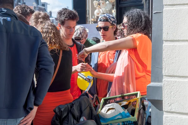 AMSTERDAM-ABRIL 27: Mujer no identificada vende gas de la risa en la calle Amsterdam a hombres jóvenes durante el Día del Rey el 27 de abril de 2015 en Ámsterdam, Países Bajos . — Foto de Stock