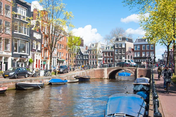 AMSTERDAM-ABRIL 30: Paisaje urbano de Ámsterdam con fila de coches, bicicletas y barcos estacionados a lo largo del canal de Ámsterdam durante el día soleado del 30 de abril de 2015, Holanda . — Foto de Stock