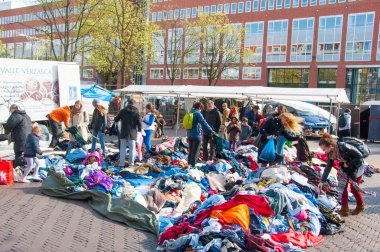 Unidentified people buy clothes in a sale on daily flea market. Amsterdam.