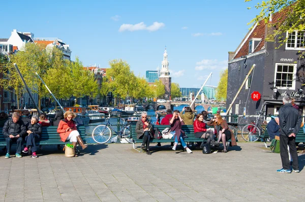 People relax in the sun, famous Cafe de Sluyswacht on the left, Montelbaans Tower is visible in the background, the Netherlands. — Stockfoto