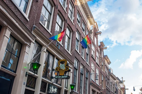 Amsterdam-30 de abril: Banderas de arco iris en el edificio medival en el distrito rojo el 30 de abril de 2015 . — Foto de Stock