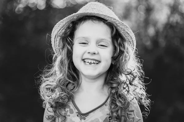 Black and white portrait of a funny little girl. Child missing tooth.