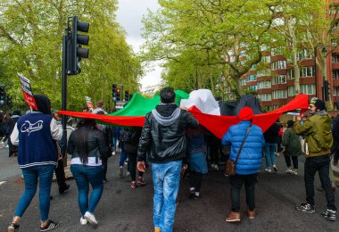 Londra, İngiltere. 15 Mayıs 2021. Filistin yanlısı protestocular çok büyük bir Filistin bayrağı altında yürüyen Özgür Filistin için Sheikh Jarrah mitinginde Birleşik Krallık hükümetini harekete geçmeye ve İsrail 'in dokunulmazlıkla hareket etmesine izin vermemeye çağırıyorlar..
