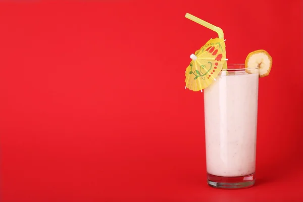 Hälsosam glas av smoothies banan smak på röd bakgrund — Stockfoto