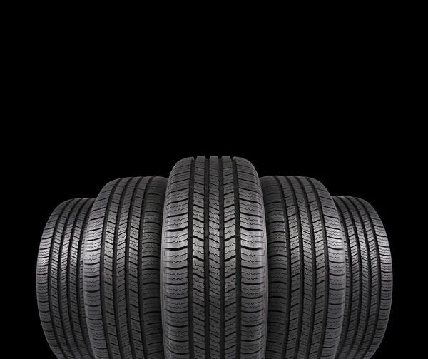 Cinq pneus en caoutchouc automobile isolés sur fond noir — Photo