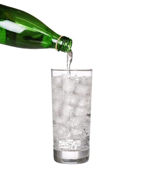 Green bottle pouring water in glass of cold mineral carbonated w — Stock Photo, Image