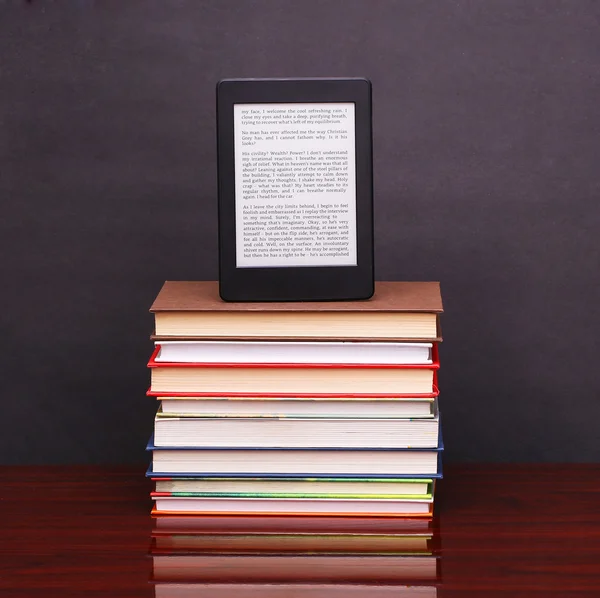 Leitor de livros eletrônicos e pilha de livros velhos sobre mesa de mesa de madeira — Fotografia de Stock